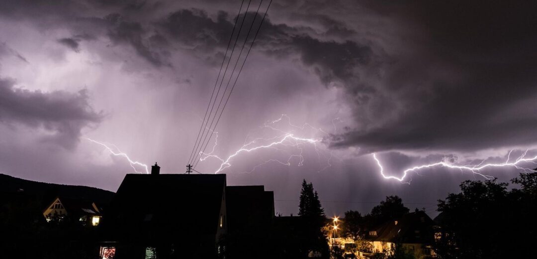 Tempestade com raios sobre casas à noite