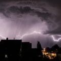 Tempestade com raios sobre casas à noite