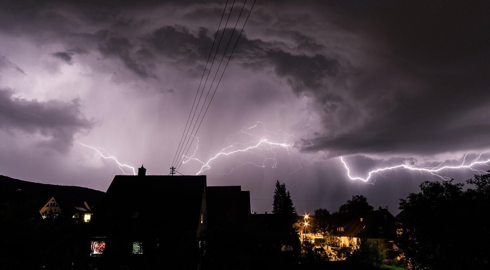 Tempestade com raios sobre casas à noite